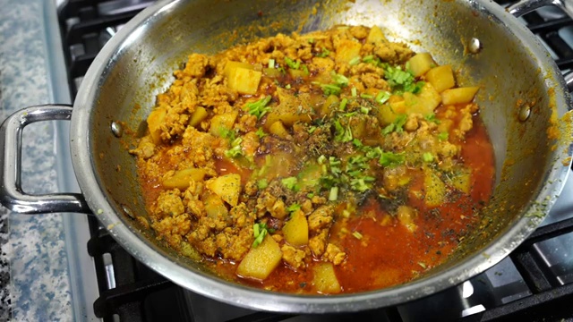 Vibrant green peas added to the cooked chicken keema and potato curry