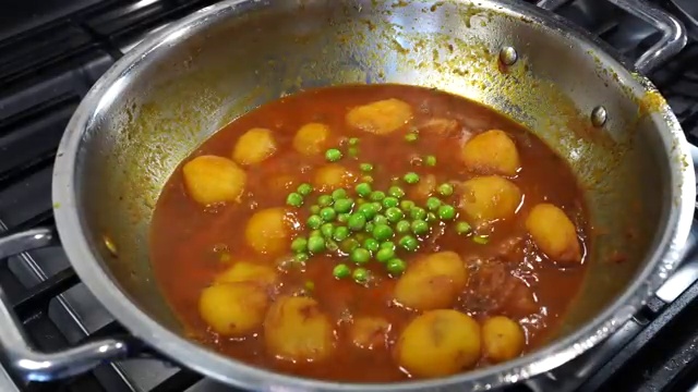 Sweet green peas added to the simmering baby potato curry
