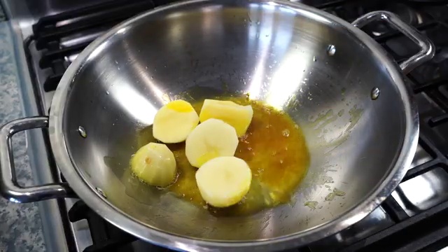 Halved potatoes frying in hot turmeric-infused oil in the skillet