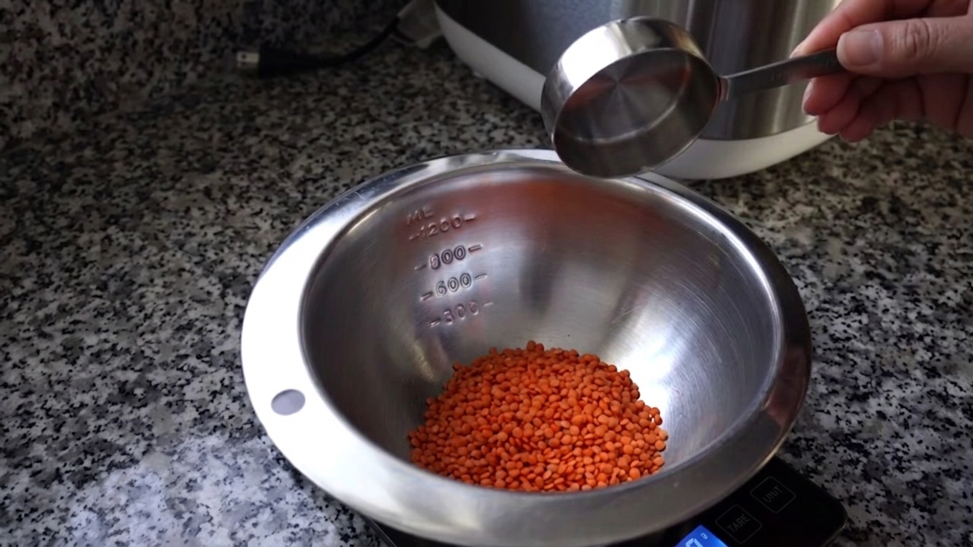 Hot water poured over red lentils, onions, garlic, and turmeric in a cooking pot