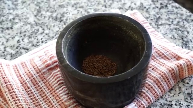 Knife testing the tenderness of a simmered baby potato in the curry