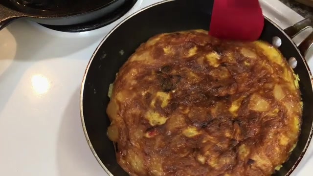 Large plate placed securely over the pan before carefully flipping the Spanish omelette