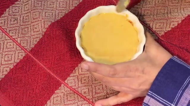 Mango crème caramel inverted onto a white serving plate with caramel sauce flowing around it