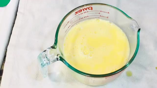 Mango custard being strained through a fine mesh sieve