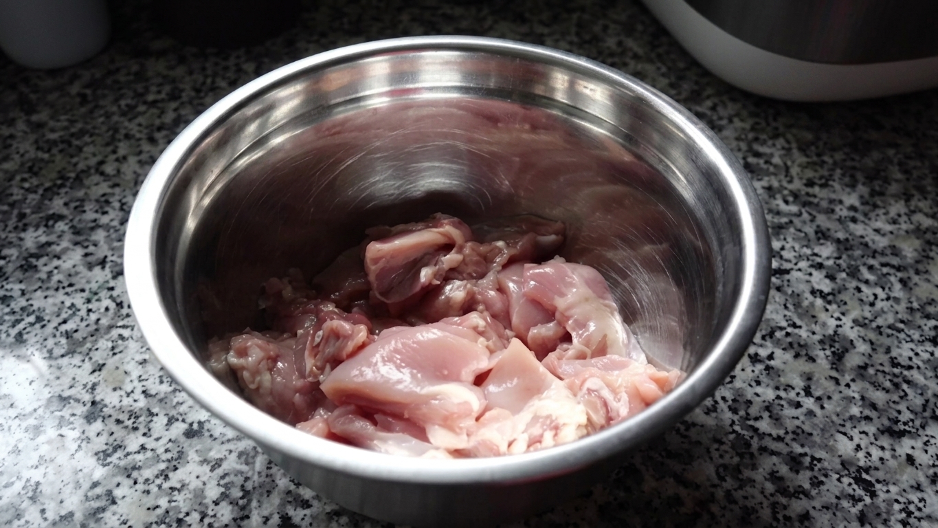 Raw chicken thigh pieces thoroughly coated and mixed with the dark soy and spice marinade
