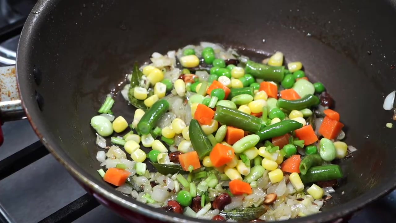 Mixed vegetables cooking with onions and spices in a wide pan