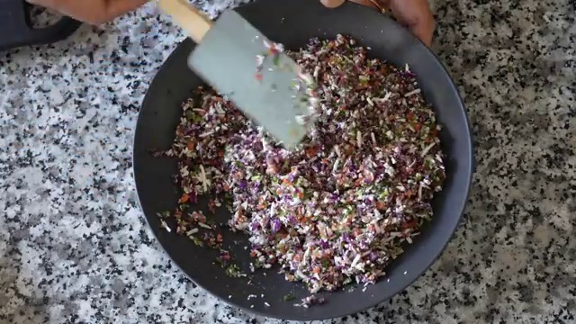 Lentil batter being spread gently in expanding circular motions with the back of a spoon into a thin crepe