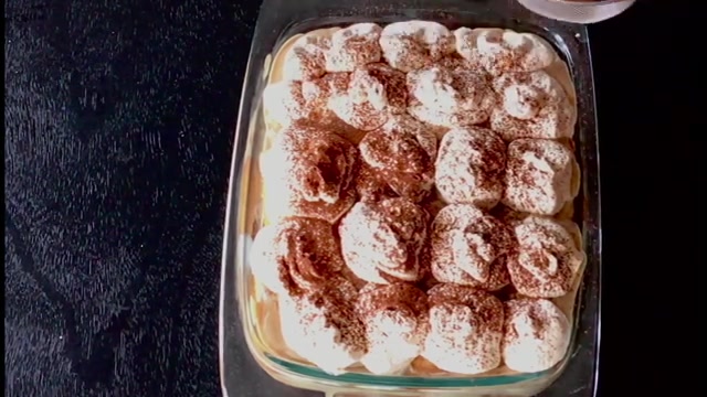 Multiple layers of plain cake, coffee custard, and cocoa powder visible through a glass trifle dish