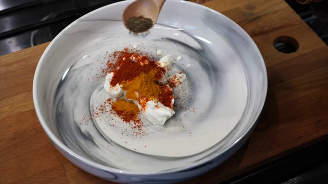 Cooking oil being poured into the yogurt-based tandoori marinade for moisture
