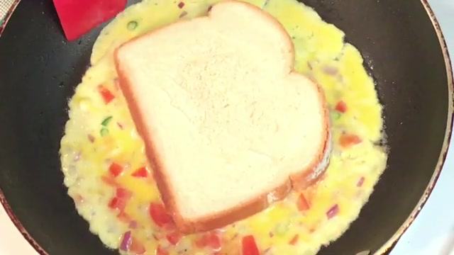 Omelette edges being folded over the bread while the egg is still slightly runny