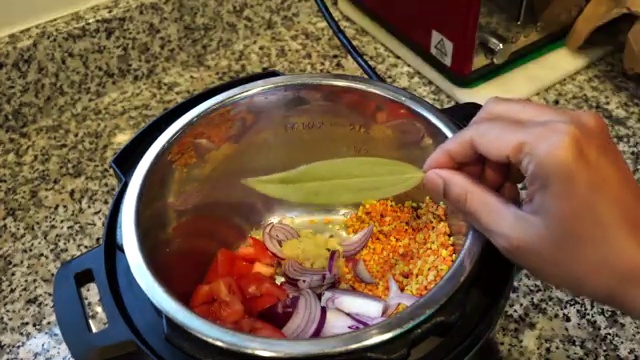 Pressure cooker lid opened revealing cooked, soft, golden moong and masoor lentils