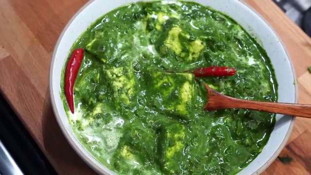 Bowl of hot Palak Paneer beautifully garnished with a drizzle of fresh cream