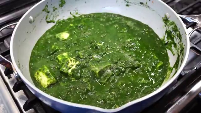 Paneer cubes simmering gently in the bright green spinach gravy for two minutes