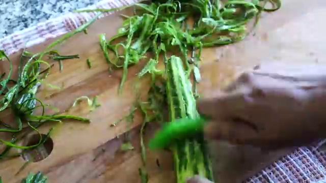 Fresh ridge gourd partially peeled in alternating strips and sliced into thick chunks