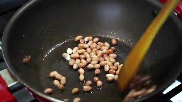 Peanuts frying in a pan until golden brown