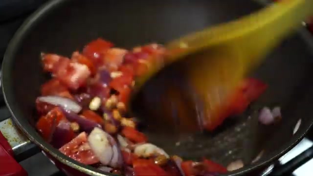 Peanuts, onion, garlic, dried chili, and tomatoes cooking together in a pan
