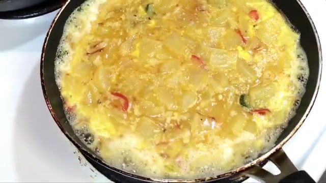 Potato and egg mixture evenly spread across a non-stick frying pan