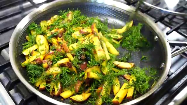 Potatoes and dill leaves stir-frying together uncovered over medium-high heat
