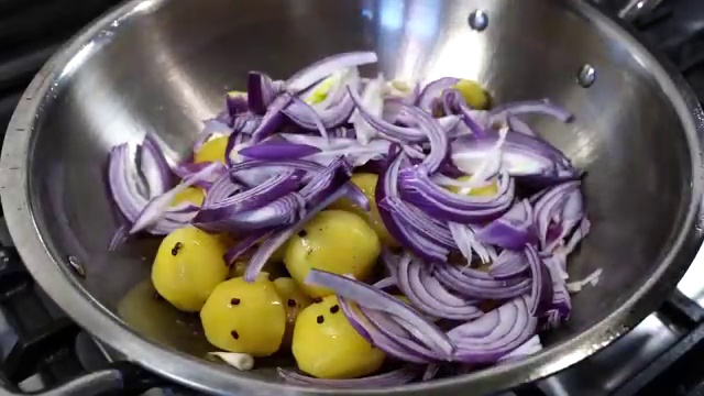 Baby potatoes and sliced onions frying together until onions are lightly golden