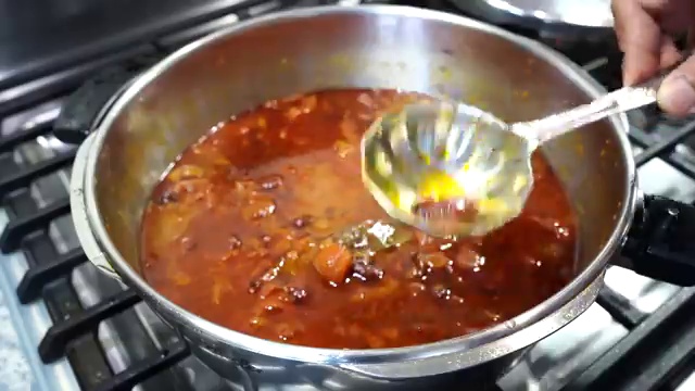 Tasting the rich Bengali rajma curry to adjust salt and sweetness before serving