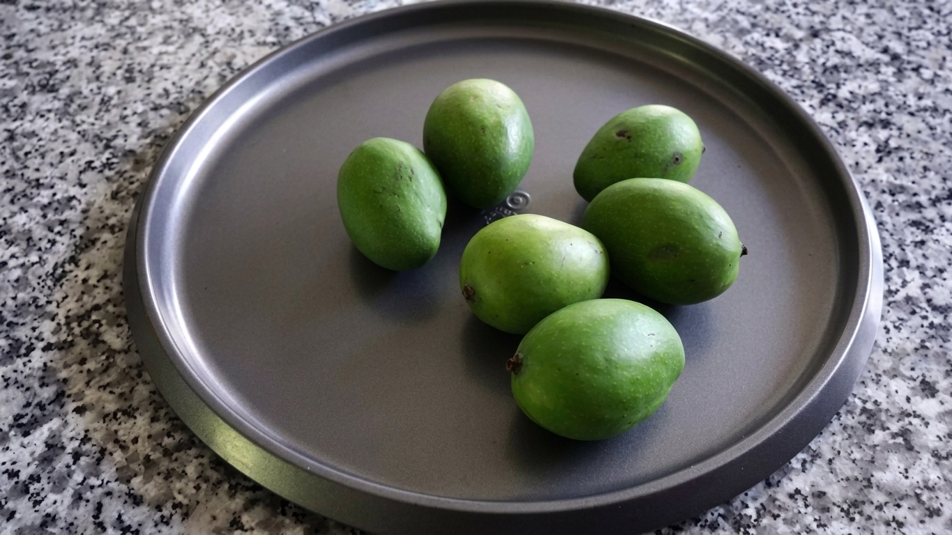 Raw green mangoes with the stem ends neatly trimmed off before peeling