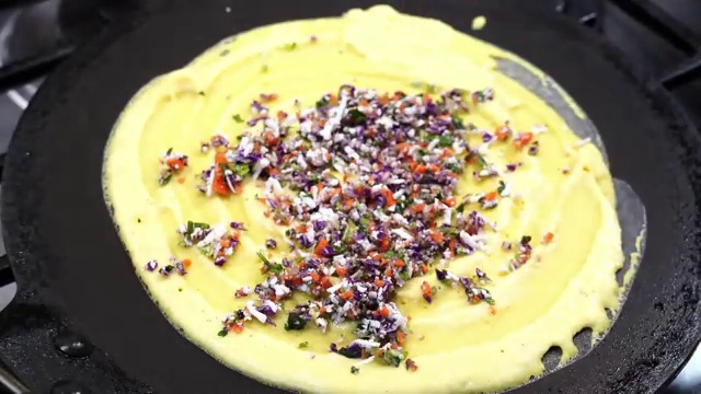 Shredded vegetable filling sprinkled over raw moong dal batter in an alternative open-faced cooking method