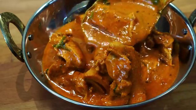 Restaurant-style Ultimate Butter Chicken plated in a bowl and drizzled with fresh cream