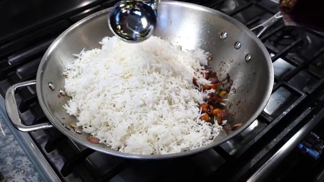 Rice being stir-fried over high heat with cauliflower Manchurian, peppers, and garlic butter