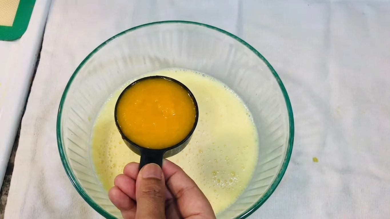 Ripe sweet mangoes cut open beside a bowl of smooth fresh mango puree