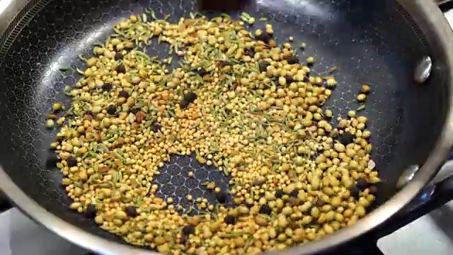 Cooled roasted whole spices placed inside a blender jar for coarse grinding