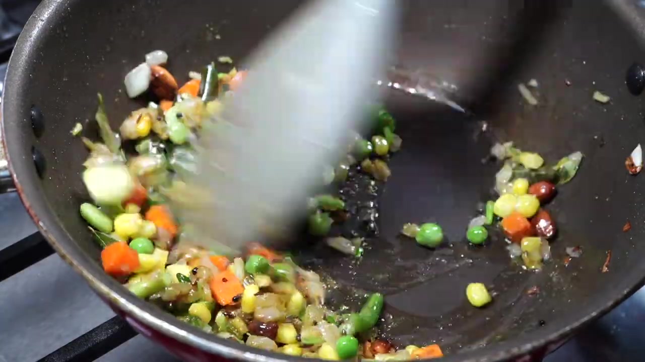 Roasted vermicelli being mixed with vegetables, onions, and Indian spices