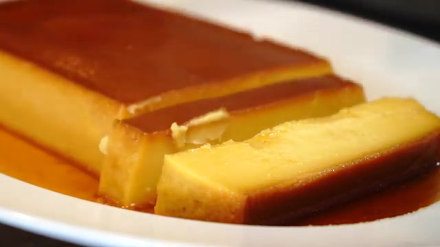 Sliced eggless mango caramel custard with caramel sauce naturally flowing over the top