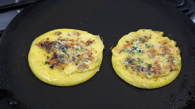 Small mini moong dal chillas cooking on a tawa ideal for children and lunchbox meals