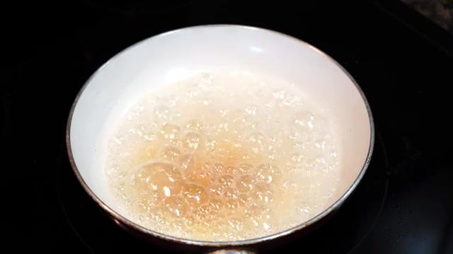 Sugar syrup bubbling in a pan as it begins turning golden
