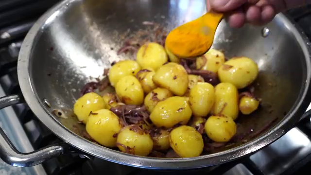 Turmeric, Kashmiri chili powder, sugar, and chopped tomatoes added to the potatoes