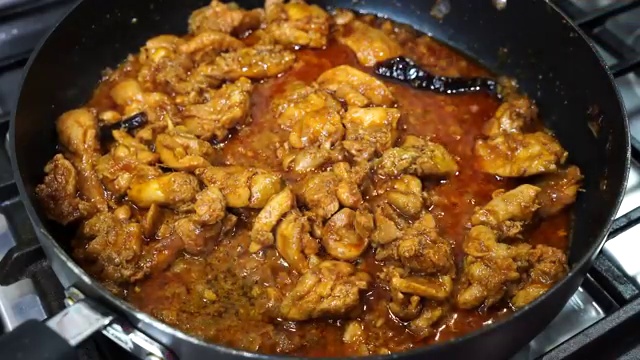 Lid removed from skillet revealing cooked juicy chicken pieces in savory sauce