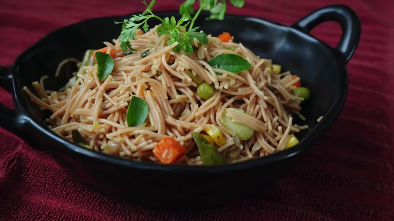 Vermicelli upma served in a bowl with fresh coriander, lemon wedges, and a fried egg