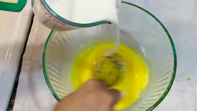 Warm milk gradually being whisked into the egg mixture for custard