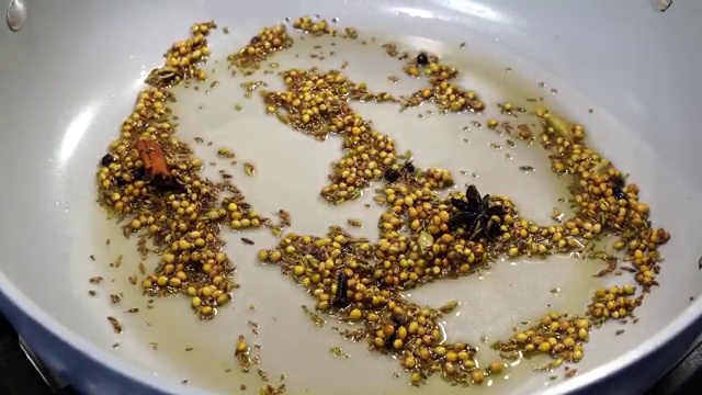 White poppy seeds added to the toasted coconut and spice mixture in the pan
