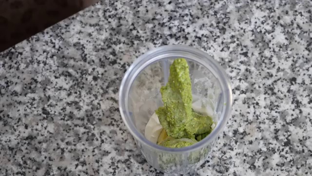 Plain yogurt, fresh avocado half, herbs, and seasonings placed inside a blender jar