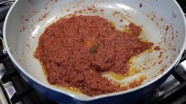 Whisked yogurt and gram flour spice slurry slowly added into the cooked tomato masala